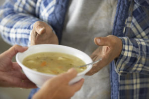 Volunteer giving bowl of soup to survivor